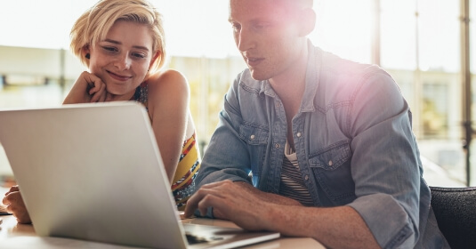 Mann und Frau während einer Weiterbildung schauen auf einen Laptop