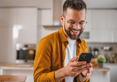 Mann mit Brille schaut auf sein Handy und lacht